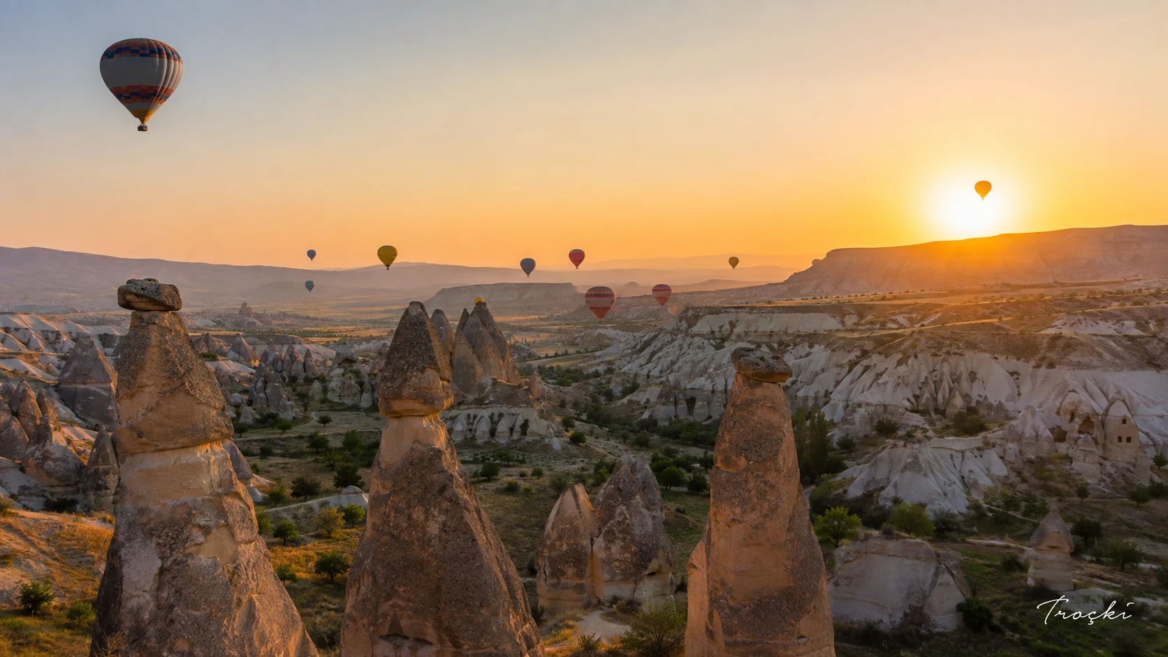 Kapadokya peri bacaları üzerinde gün doğumunda süzülen balonlar
